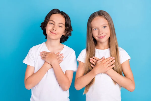 Foto retrato niños manteniendo las manos juntas manos en el pecho aislado pastel color azul fondo —  Fotos de Stock