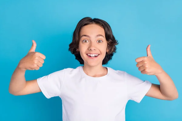 Foto Porträt Schuljunge lächelt aufgeregt in weißem T-Shirt zeigt Daumen-hoch-Zeichen isoliert pastellblauen Farbhintergrund — Stockfoto