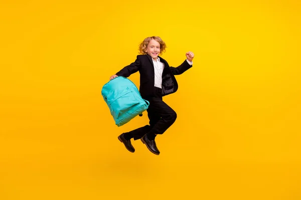 Фото веселого стрибка школяра носіть рюкзак шкільний одяг уніформа ізольований жовтий колір фону — стокове фото
