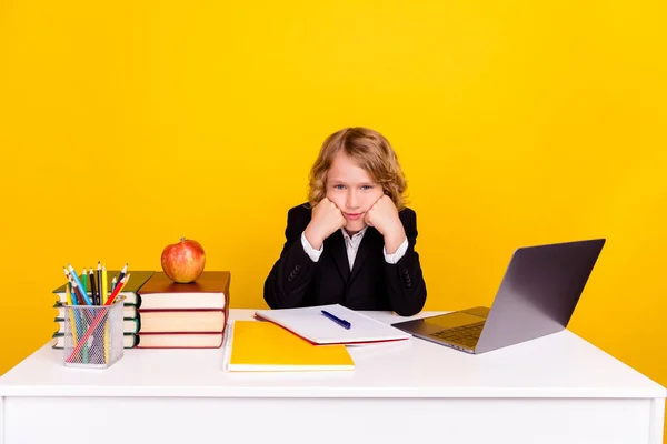 Foto av uttråkad trött skolbarn sitta skrivbord händer kinder bryta lektion bära uniform isolerad gul färg bakgrund — Stockfoto