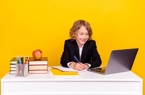 Foto de estudante inteligente positivo sentar olhar netbook escrever notas desgaste uniforme isolado cor amarela fundo — Fotografia de Stock