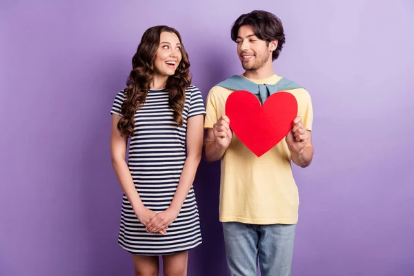 Foto de doces amantes animados vestida roupa casual subindo grande coração vermelho sorrindo isolado cor roxa fundo — Fotografia de Stock