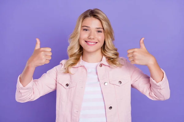 Фото милої блискучої шкільної дівчини, одягненої в рожевий одяг, посміхається, показуючи два великі пальці вгору ізольований фіолетовий кольоровий фон — стокове фото
