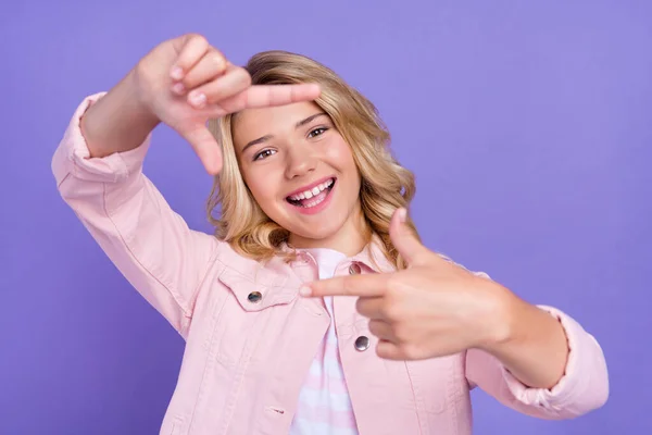 Foto di lucido adorabile ragazza della scuola vestita di rosa vestiti sorridente mostrando foto sparare gesto isolato colore viola sfondo — Foto Stock