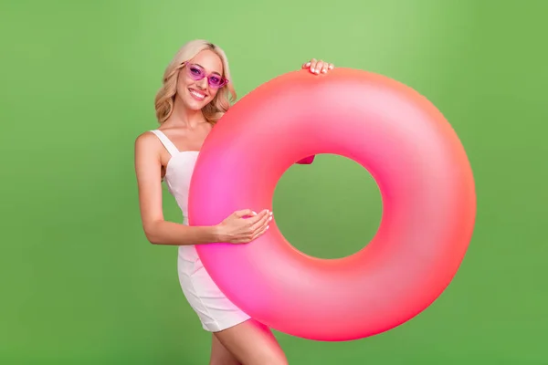 Foto di sorridente bella femmina tenere cerchio acqua godere di piscina partito estate fine settimana isolato su sfondo di colore verde — Foto Stock