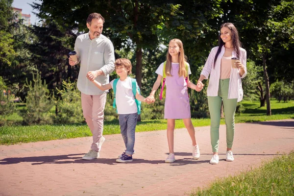 Foto de muito doce preteen menino menina mãe pai vestido roupa casual segurando braços andando segurando bebidas fora do parque da cidade — Fotografia de Stock