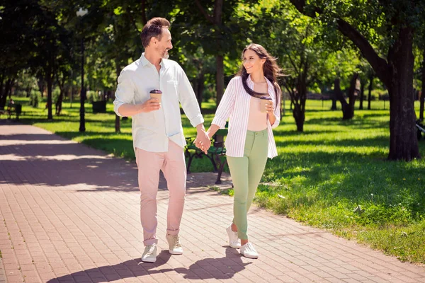 Photo of charming cute ojciec matka nosić casual ubrania spaceru trzymając ręce pijąc herbatę uśmiechnięty na świeżym powietrzu las — Zdjęcie stockowe