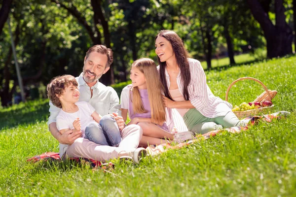 Foto de família doce brilhante vestir roupas casuais sorrindo tendo piquenique sentado manta xadrez ao ar livre parque urbano da cidade — Fotografia de Stock