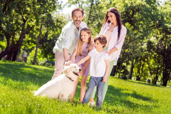 Foto de dulce encanto preadolescente niña madre padre vestido traje casual jugando pappy sonriendo fuera del parque de la ciudad — Foto de Stock