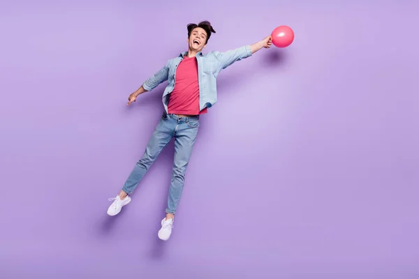 Foto de cuerpo entero del joven feliz sonrisa positiva volar globos de aire decoración aislado sobre fondo de color púrpura —  Fotos de Stock