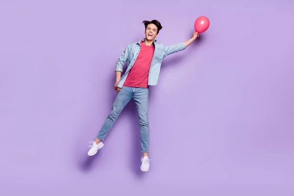 Pleine longueur photo de jeune gars heureux sourire positif anniversaire saut mouche ballons isolé sur fond de couleur pourpre — Photo