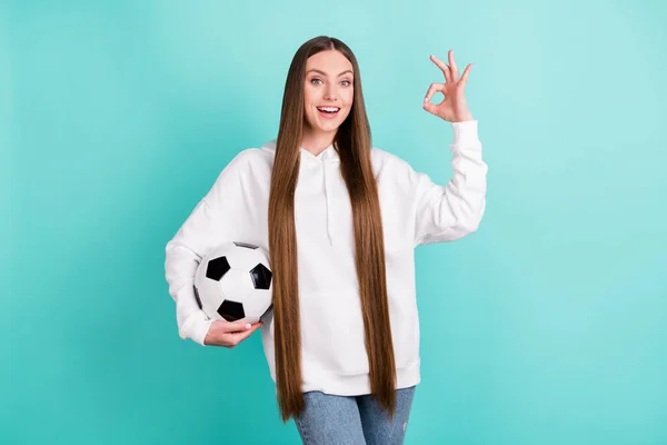 Retrato de atractiva chica alegre sosteniendo la pelota mostrando ok-signo aislado sobre fondo de color turquesa verde azulado brillante — Foto de Stock