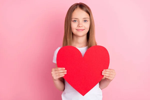 Foto de linda menina loira segurar coração desgaste branco t-shirt isolado no fundo cor-de-rosa — Fotografia de Stock