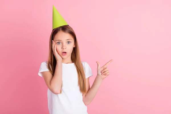 Foto van onder de indruk blond klein meisje hand wang punt lege ruimte dragen hoed wit t-shirt geïsoleerd op roze kleur achtergrond — Stockfoto