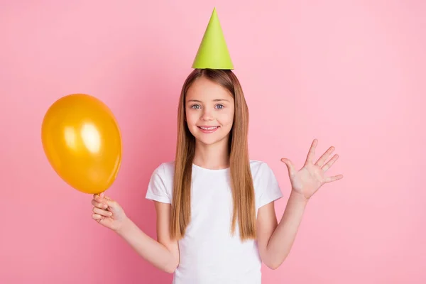 Foto de agradável loira pequena menina mostrar cinco segurar balão desgaste chapéu branco t-shirt isolado no fundo cor-de-rosa — Fotografia de Stock