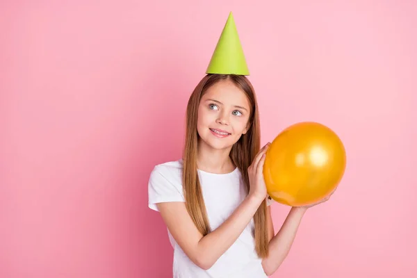 Foto van funky blond klein meisje houden ballon look lege ruimte dragen hoed wit t-shirt geïsoleerd op roze kleur achtergrond — Stockfoto