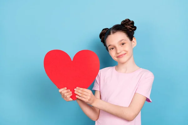 Фото веселой молодой счастливой позитивной маленькой девочки держаться за руки красной бумаги сердце изолированы на синем фоне цвета — стоковое фото