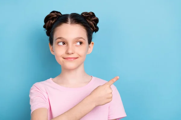 Foto von charmanten süßen Schulmädchen gekleidet rosa T-Shirt suchen Zeigefinger leeren Raum isoliert blaue Farbe Hintergrund — Stockfoto