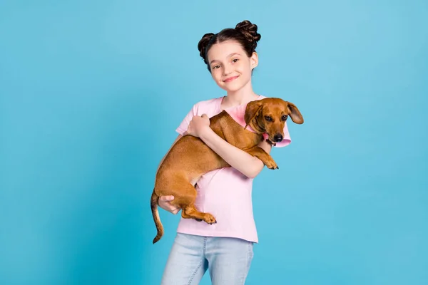 Foto di carino affascinante ragazza della scuola indossare rosa t-shirt sorridente tenendo le braccia mani piccolo amico isolato colore blu sfondo — Foto Stock