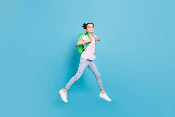 Foto de brillante niña bonita escuela usar rosa camiseta mochila sonriente caminar saltando alto aislado color azul fondo — Foto de Stock