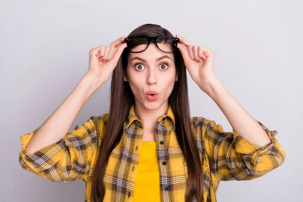 Fotografie rozkošné šokované mladé ženy oblečené kostkované košile brýle velké oči rty našpulené izolované šedé pozadí — Stock fotografie