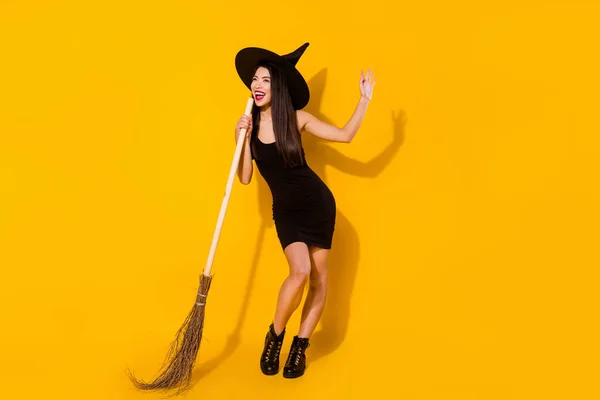 Pełny rozmiar zdjęcie śpiewać czarownica millenium lady z miotły nosić czarny sukienka czapka buty izolowane na żółtym tle — Zdjęcie stockowe