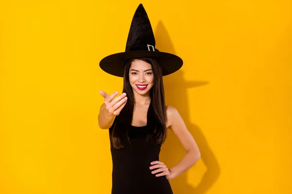 Foto de otimista jovem morena hairdo senhora pedir-lhe para vir usar vestido preto bruxa cap isolado no fundo de cor amarela — Fotografia de Stock