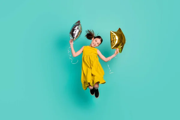 Full size photo of impressed nice brown hair girl hold balloons jump wear yellow dress isolated on bright teal color background — Stock Photo, Image