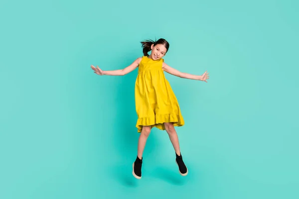 Полноразмерная фотография впечатляющей красивой коричневой девушки, прыгающей в желтом платье, изолированном на ярком цветовом фоне — стоковое фото