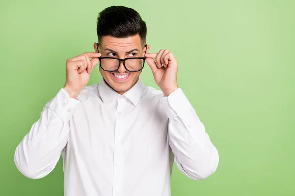 Foto de muito engraçado jovem cavalheiro desgaste branco camisa braços óculos olhando espaço vazio isolado cor verde fundo — Fotografia de Stock
