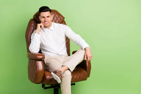 Photo of confident thoughtful young gentleman wear white shirt smiling sitting leather chair empty space isolated green color background — Stock Photo, Image
