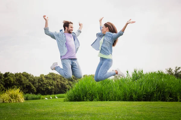 Pełnowymiarowe zdjęcie uśmiechniętego dobrego nastroju para skoków podnieść ręce w zwycięstwie triumf cieszyć się wakacjami — Zdjęcie stockowe
