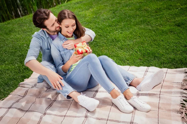 Full size foto van lachend positief paar hebben picknick buiten in park vriendje geven verrassing doos naar vrouw romantisch date — Stockfoto