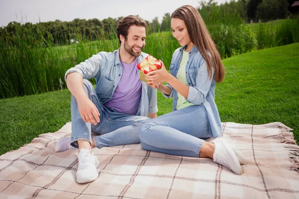 Foto de casal sorrindo de bom humor desfrutando ao ar livre comemorar aniversário mulher aberta caixa surpresa relaxante no parque — Fotografia de Stock