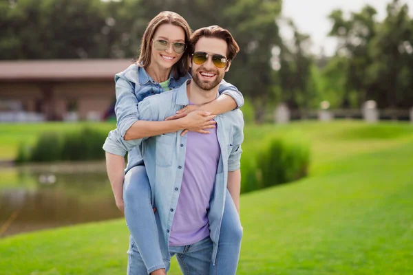 Foto de sorrindo positivo casal sair juntos relaxante verão férias marido segurar esposa piggyback — Fotografia de Stock