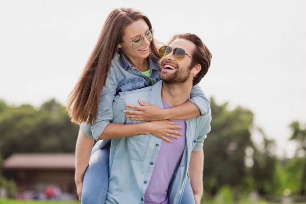 Foto de buen humor positivo encantadora linda pareja divirtiéndose al aire libre marido celebrar esposa piggyback engañando alrededor — Foto de Stock