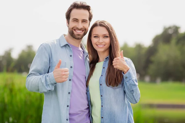 Foto van lachende vrolijke positieve paar vrouw en man tonen duim-up aanbevelen product adverteren product ontspannen buiten — Stockfoto