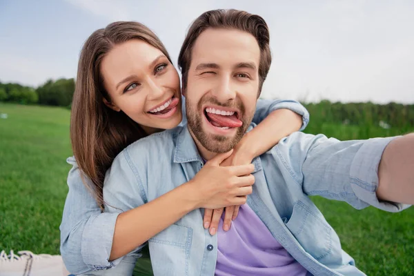 Foto de casal sorrindo engraçado funky tomar selfie brincando mostrar língua comportamento infantil relaxante ao ar livre fora — Fotografia de Stock