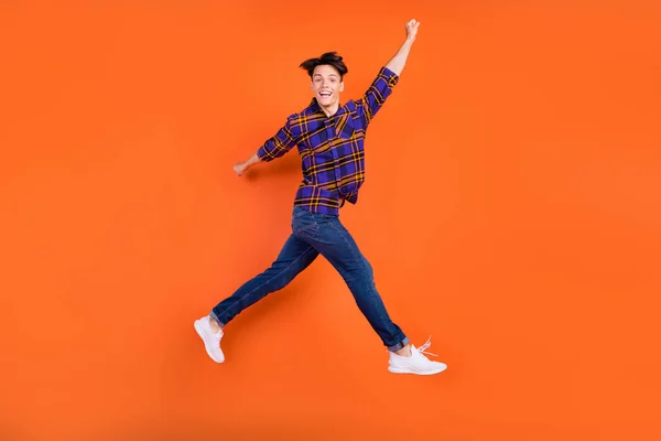 Foto de perfil de corpo inteiro do cara engraçado millennial salto desgaste camisa jeans tênis isolado no fundo laranja — Fotografia de Stock
