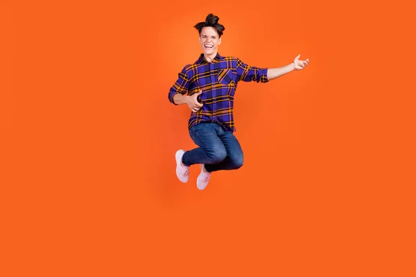 Foto do funky bonito adolescente menino desgaste xadrez roupa óculos sorrindo saltando alto tocando guitarra isolado cor laranja fundo — Fotografia de Stock