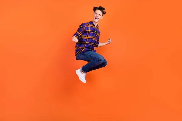 Foto em tamanho completo de millennial hooray cara salto desgaste camisa jeans tênis isolado no fundo laranja — Fotografia de Stock