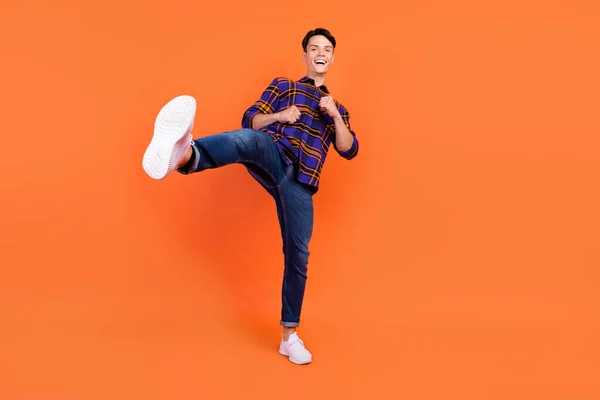 Foto de longitud completa de millennial funky chico lucha desgaste camisa jeans zapatillas aisladas sobre fondo naranja —  Fotos de Stock