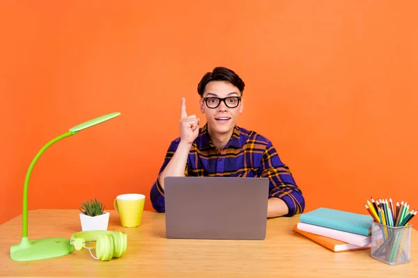 Bild av ung cool kille typ laptop peka upp bära rutig skjorta glasögon isolerade på orange bakgrund — Stockfoto