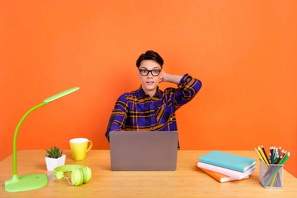 Foto de millennial impressionado cara tipo laptop desgaste xadrez camisa óculos isolados no fundo laranja — Fotografia de Stock