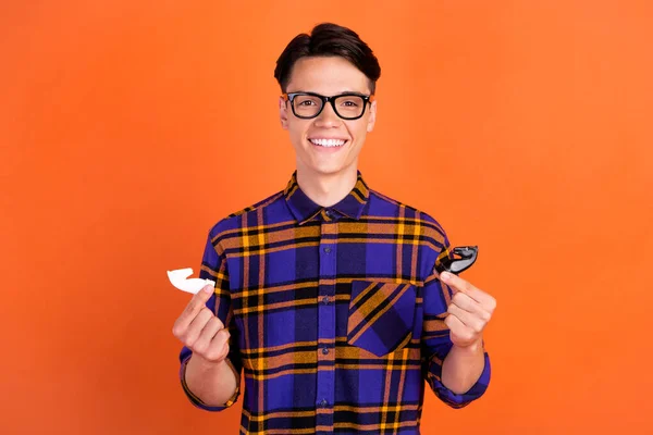 Fotografie tisíciletý legrační chlap hrát šachové oblečení kostkované košile brýle izolované na oranžové barvy pozadí — Stock fotografie