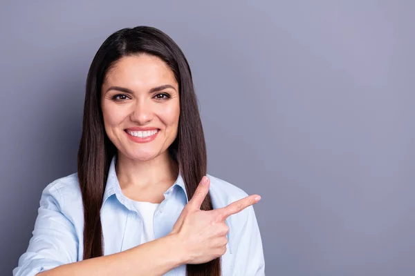 Foto de encantador doce mulher madura usar camisa formal sorrindo apontando dedo vazio espaço isolado cinza cor fundo — Fotografia de Stock