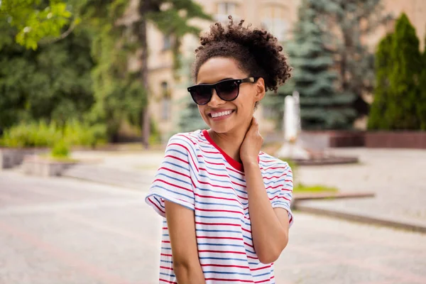 Foto de joven atractiva chica negra feliz sonrisa positiva hacer selfie mano tacto cuello caminar usar gafas de sol al aire libre — Foto de Stock