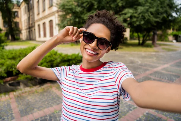Zdjecie mlodej wesolej Afryki dziewczyna szczesliwy pozytywny usmiech uczynic selfie reka dotknac sunglass wycieczka lato na zewnatrz — Zdjęcie stockowe