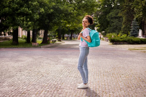 Pełna długość profil strona zdjęcie młody czarny kobieta szczęśliwy pozytywny uśmiech trzymać plecak student zewnątrz — Zdjęcie stockowe