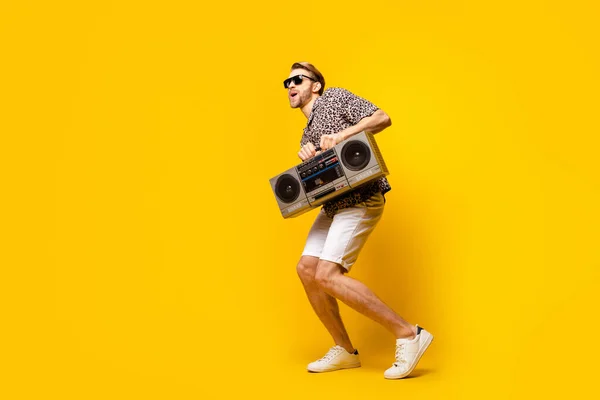 Volledige lengte foto van vrij grappige jonge man dragen luipaard outfit donker brillen dansen boom doos geïsoleerde gele kleur achtergrond — Stockfoto